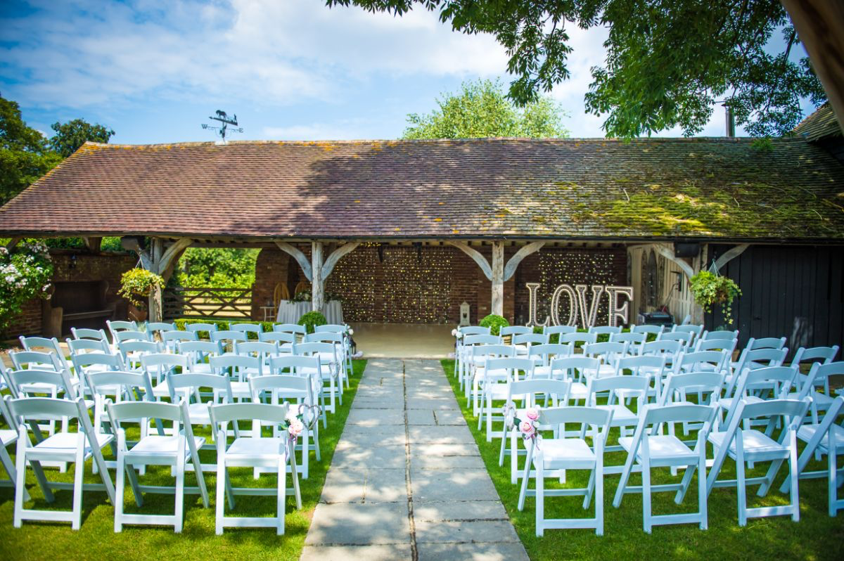 Outdoor ceremony setup with white chairs and LOVE sign